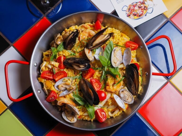Colorful seafood paella served in a pan on a tiled table, perfect for food presentations.